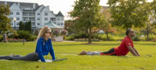 a man and woman doing yoga poses on the lawn