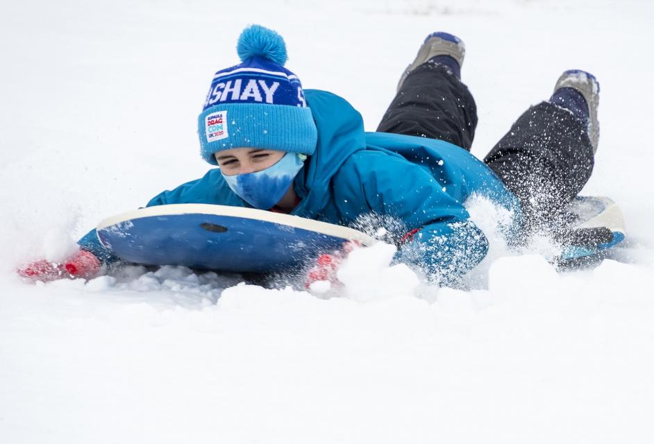 boy sledding down a snowy hill